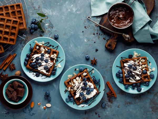 Chocolate waffles with cream, blueberries and chocolate sauce, seen from above