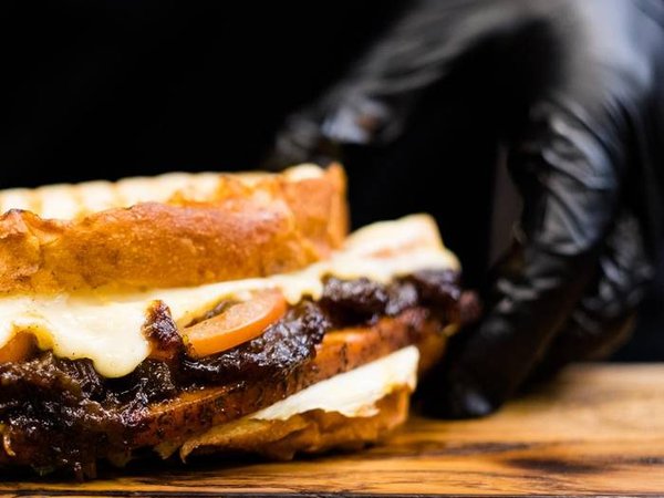 Professional catering. Chef hands serving smoked turkey breast sandwich on wooden board.