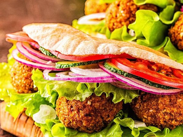 Falafel and fresh vegetables in pita bread on dark background.