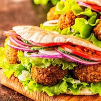 Falafel and fresh vegetables in pita bread on dark background.