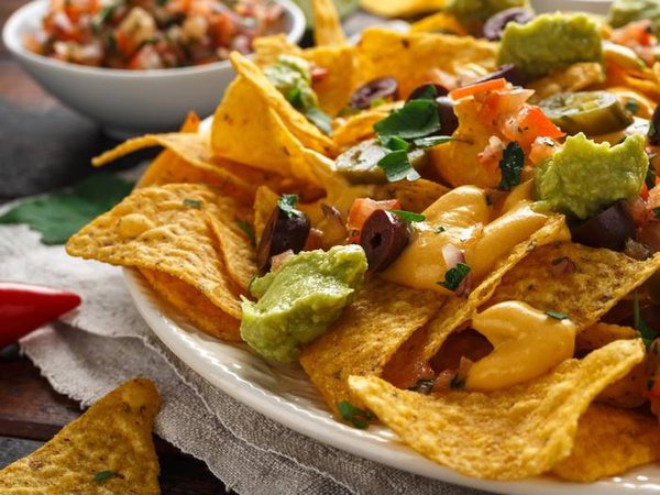 Mexican nachos tortilla chips with olives, jalapeno, guacamole, tomatoes salsa, cheese dipand beer.