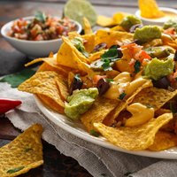 Mexican nachos tortilla chips with olives, jalapeno, guacamole, tomatoes salsa, cheese dipand beer.