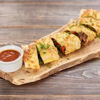 Spicy mexican burrito with sauce. Delicious burrito brunch cutted in pieces and served with fresh chili pepper with basil.