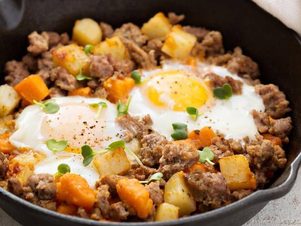Potato and sweet potato hash with eggs in cast iron pan