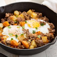 Potato and sweet potato hash with eggs in cast iron pan