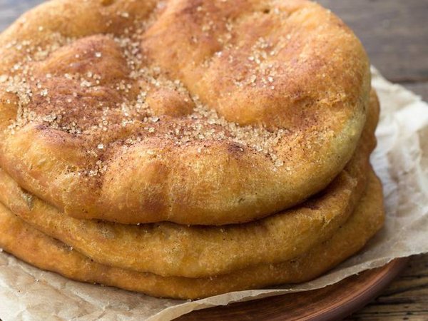 Homemade Navajo fried bread or sweet Elephant Ears with brown sugar and cinnamon on wooden table, selective focus