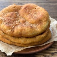 Homemade Navajo fried bread or sweet Elephant Ears with brown sugar and cinnamon on wooden table, selective focus