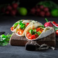 Tacos with spicy sauce and coriander on concrete table