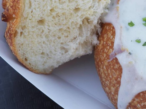 Close-up of clam chowder served in sourdough bread bowl and garnished with herbs, a delicious traditional American street food found at vendors or restaurants in San Francisco, California, US