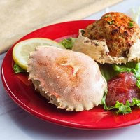 Stuffed seasoned crab shells garnished with romaine lettuce and sliced lemon with cocktail sauce