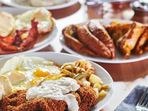 chicken fried steak covered in gravy with sunny side up eggs and breakfast foods