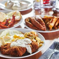 chicken fried steak covered in gravy with sunny side up eggs and breakfast foods