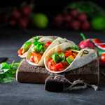 Tacos with spicy sauce and coriander on concrete table