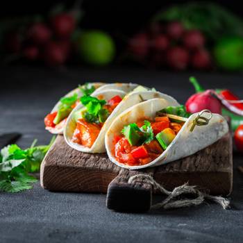 Tacos with spicy sauce and coriander on concrete table