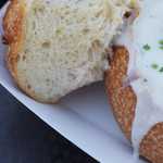 Close-up of clam chowder served in sourdough bread bowl and garnished with herbs, a delicious traditional American street food found at vendors or restaurants in San Francisco, California, US